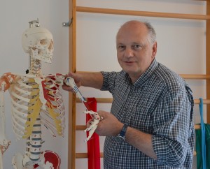 Herr Detlef Miebs steht neben einem farblich markierten Skelett und hebt den linken Arm hervor