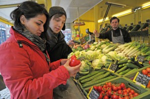 Frau prüft eine Paprika an einem Gemüsestand