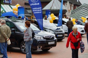 Besucher stehen vor einem schwarzen Subaru- und Ford-Modell.