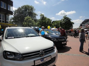 Das Foto zeigt ein weißes und schwarzes VW-Modell sowie interessierte Besucher.