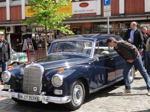 Ein blauer Mercedes Oldtimer wird von einem Besucher genauer betrachtet.