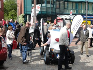 Ein Besucher testet ein kleines Ein-Mann-Auto bei der Autoschau Tibarg 2012 und wird dabei von anderen Interessierten beobachtet.