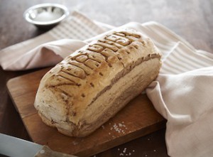 Das Foto zeigt ein knuspriges Brot mit der Einprägung "Nur Hier" auf einem Holzbrett.