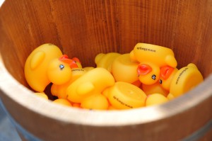 Mehrere gelbe, kleine Spielzeugenten in einem hölzernen Eimer