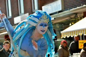 Eine Künstlerin in fantasievoller, blauer Kleidung und Kopfschmuck unterhält die Besucher.