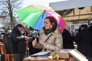 An einem Aktionsstand mit Flyern steht eine Frau mit einem bunten Tibarg-Schirm.