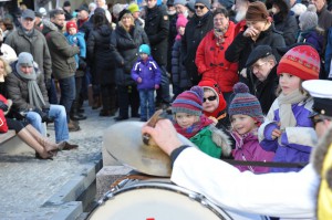 Kinder und Erwachsene beobachten in direkter Nähe zum Brunnen eine musikalische Darbietung