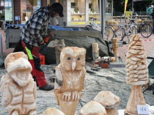 Ein Mann schneidet aus Holzstücken mit einer Kettensäge Skulpturen.