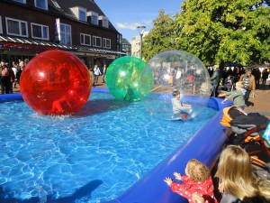 Kinder befinden sich im Inneren von aufgeblasenen Bällen und können so quasi schwerelos über das Wasser laufen