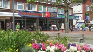 Sicht auf die Heudorfer Apotheke mit blühendem Blumenbeet im Vordergrund