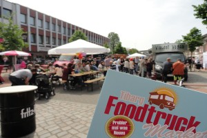 Das Schild zeigt ein Foto des Tibarg Foodtruck Festival Aufstellers vor dem Hintergrund des Festivals 2016