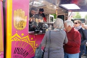 Das Foto zeigt Menschen vor einem indischen Foodtruck beim Tibarg Foodtruck Festival 2016 in Hamburg-Niendorf am Tibarg