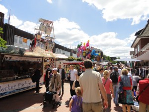 Das Foto zeigt Passanten zwischen Buden und Attraktionen auf dem Tibargfest.