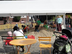 Kinder spielen mit Backformen auf einem Sandhaufen beim Tibargfest.