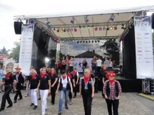 Eine Gruppe von Tänzern mit rotem Halstuch performt Line Dance vor der Bühne auf dem Tibargfest.