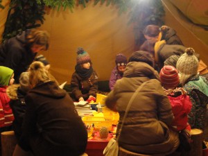 Kinder basteln mit Hilfe von Erwachsenen in einem Zelt kleine Kunstwerke.