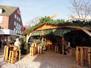 Das Foto zeigt eine Weihnachtsmarkt-Hütte bei Tag und im Sonnenlicht.