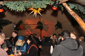 Im Tipi-Zelt stehen Besucher an Stehtischen zusammen und genießen ihre Getränke.