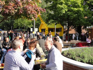 Besucher sitzen weintrinkend auf Bierzeltgarnituren. Im Hintergrund ist eine Hüpfburg für Kinder aufgebaut.