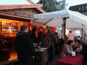 Das Foto zeigt Besucher beim Weintrinken vor einem Getränkestand.
