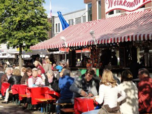 Besucher genießen auf Biergartengarnituren die Sonne sowie Wein und Speisen am Tibarg.