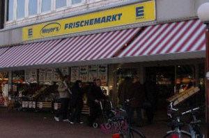 Eingang von Meyer's Frischemarkt mit Obst, Gemüse und rot-weiß-gestreiften Markisen