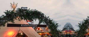 Das Bild zeigt ein Tipi mit einer Umrahmung aus Tannenzweigen auf dem "Kinderbasteltipi" steht.